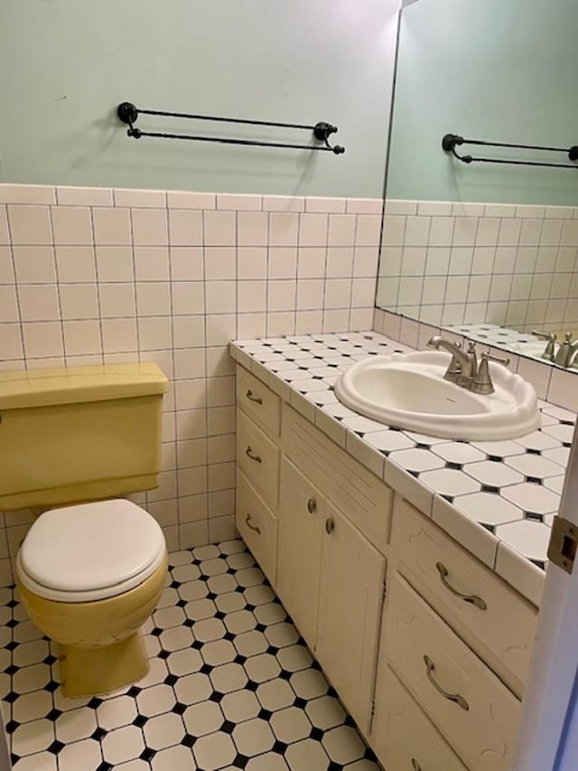 bathroom featuring vanity, toilet, and tile walls