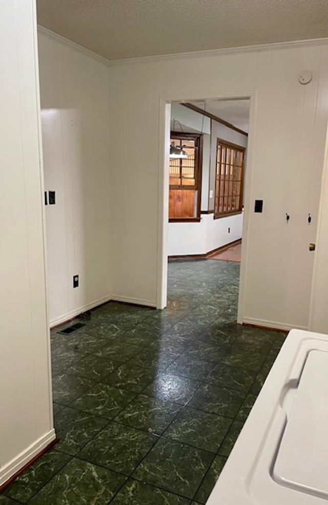 unfurnished room featuring ornamental molding and a textured ceiling