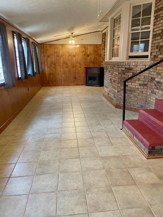 unfurnished living room featuring wooden walls and brick wall