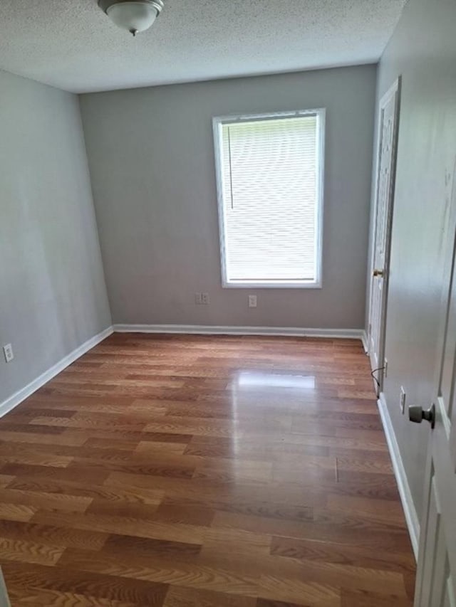 spare room with dark hardwood / wood-style flooring and a textured ceiling