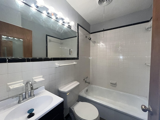 full bathroom featuring tile walls, toilet, decorative backsplash, vanity, and tiled shower / bath combo