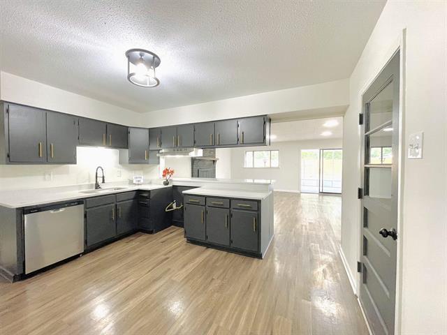 kitchen featuring stainless steel dishwasher, gray cabinetry, sink, and a textured ceiling