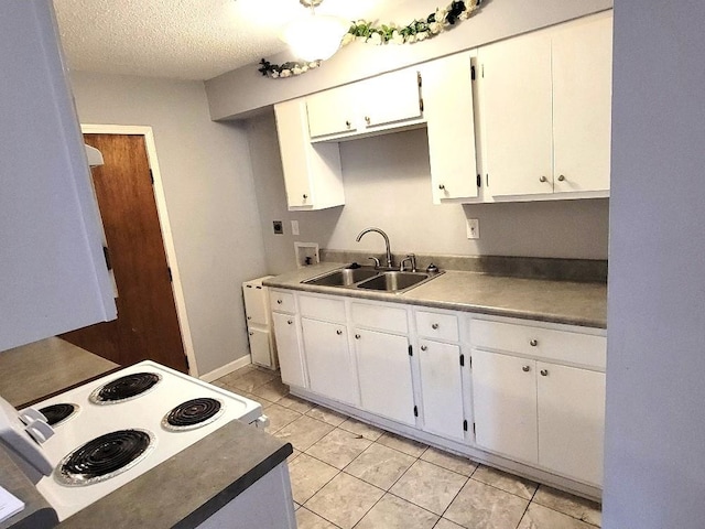 kitchen featuring white electric stove, sink, light tile patterned floors, a textured ceiling, and white cabinetry