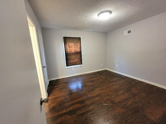 unfurnished room with dark wood-type flooring and a textured ceiling