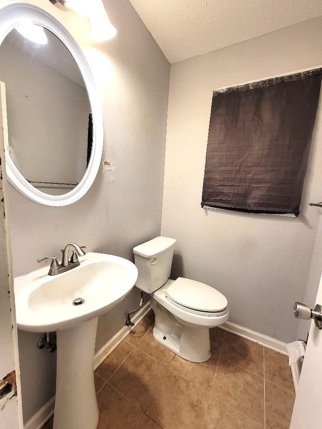 bathroom featuring tile patterned flooring, a textured ceiling, and toilet