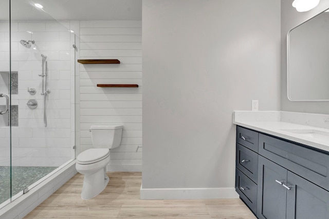 bathroom with a shower with door, vanity, and toilet