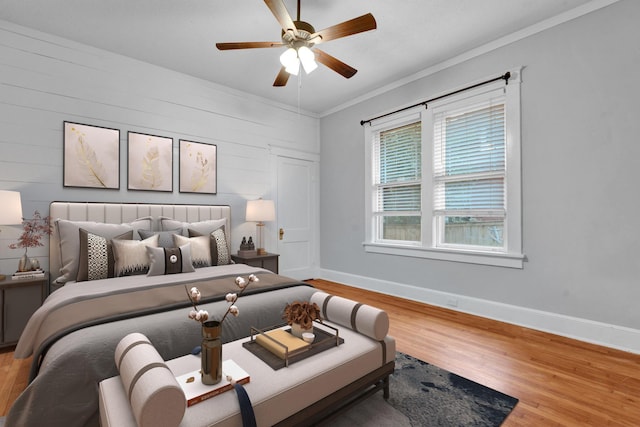 bedroom with ceiling fan, wood-type flooring, ornamental molding, and wooden walls