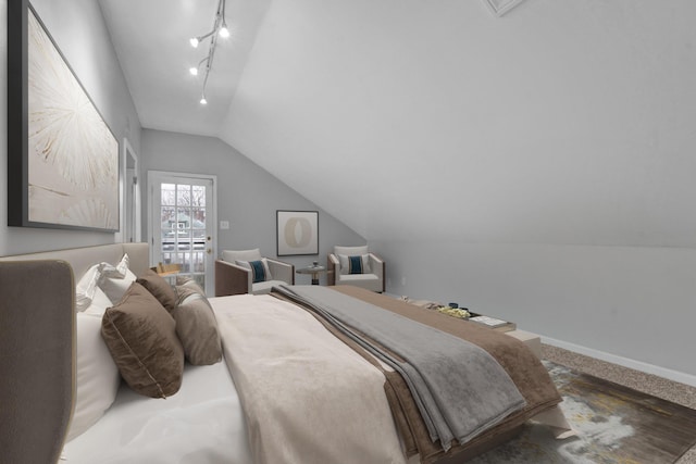 bedroom with carpet flooring, rail lighting, and lofted ceiling