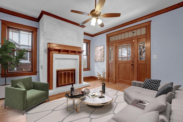 living room featuring crown molding, ceiling fan, light hardwood / wood-style floors, and a brick fireplace