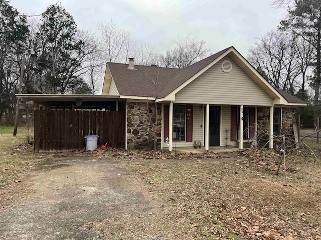 view of front of property featuring stone siding, roof with shingles, and covered porch