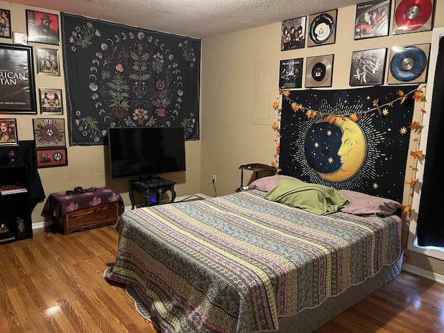 bedroom featuring a textured ceiling, baseboards, and wood finished floors