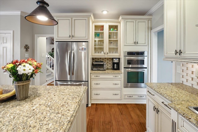 kitchen with pendant lighting, crown molding, decorative backsplash, light stone countertops, and appliances with stainless steel finishes