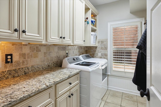 clothes washing area featuring cabinets, separate washer and dryer, and light tile patterned floors