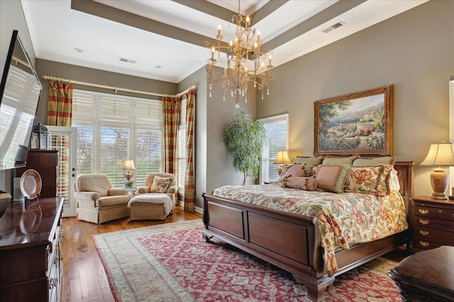 bedroom featuring hardwood / wood-style floors, crown molding, and a chandelier