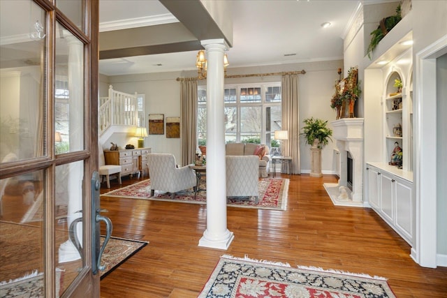 dining area with ornate columns, crown molding, built in features, and hardwood / wood-style floors