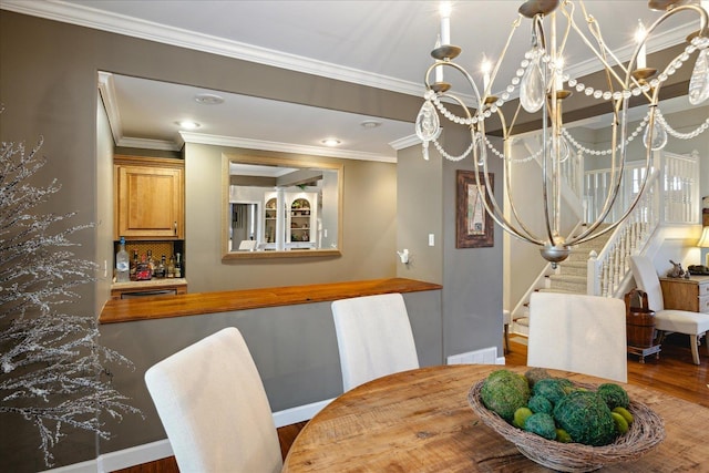 dining room with hardwood / wood-style flooring, crown molding, and a notable chandelier