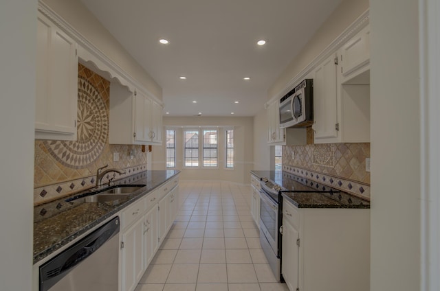 kitchen with white cabinetry, sink, stainless steel appliances, dark stone countertops, and light tile patterned flooring