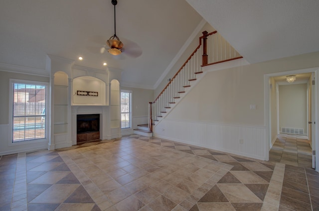 unfurnished living room with ceiling fan, a large fireplace, and ornamental molding