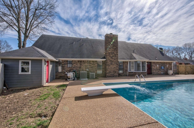 view of swimming pool with a diving board, a patio, and cooling unit