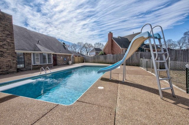 view of pool with a diving board, a patio area, and a water slide