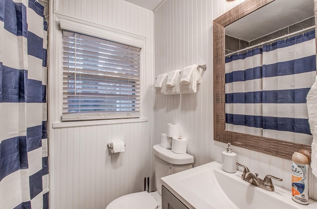 bathroom featuring vanity, wood walls, toilet, and curtained shower