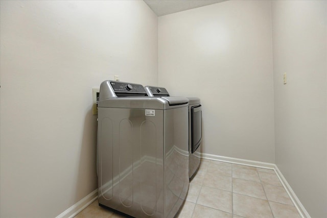 clothes washing area with washer and dryer, light tile patterned floors, and a textured ceiling