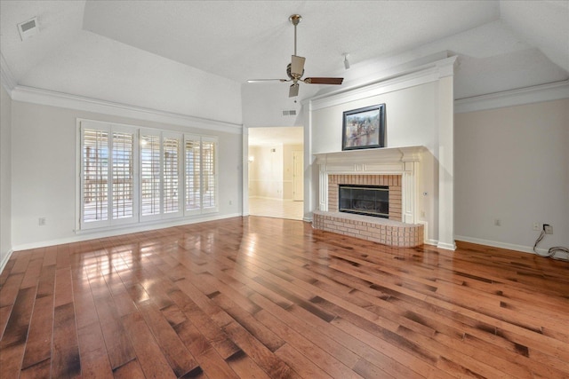 unfurnished living room with ornamental molding, a tray ceiling, ceiling fan, hardwood / wood-style flooring, and a fireplace