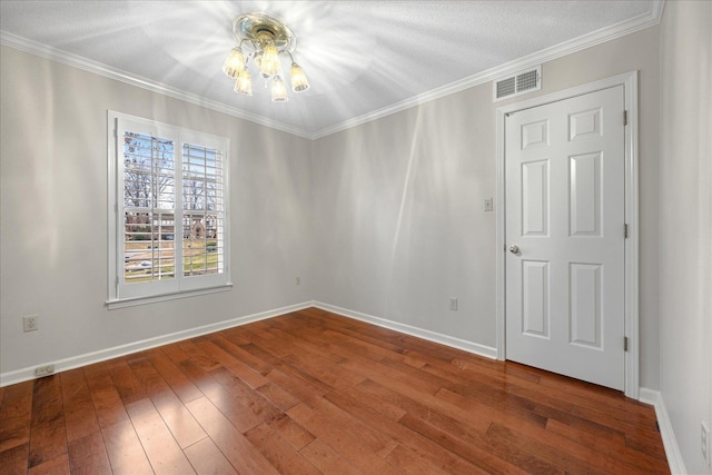 empty room featuring a textured ceiling, hardwood / wood-style flooring, an inviting chandelier, and ornamental molding