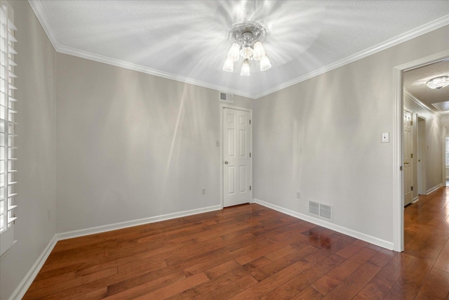 spare room with dark hardwood / wood-style flooring, crown molding, and an inviting chandelier