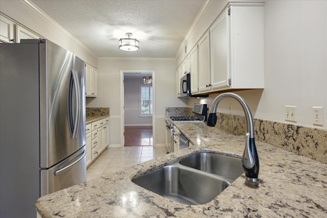 kitchen featuring light stone countertops, appliances with stainless steel finishes, ornamental molding, light tile patterned floors, and white cabinetry