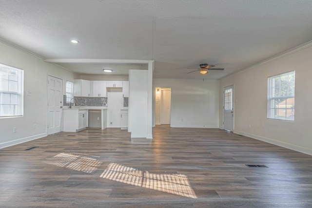 unfurnished living room featuring a textured ceiling, ceiling fan, dark hardwood / wood-style flooring, and crown molding