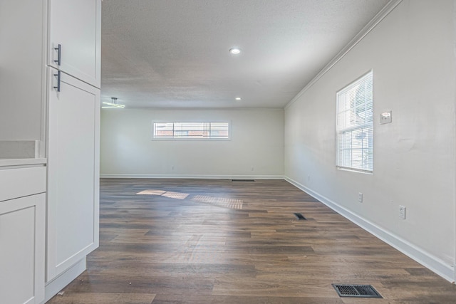 spare room with a textured ceiling, dark hardwood / wood-style flooring, and crown molding