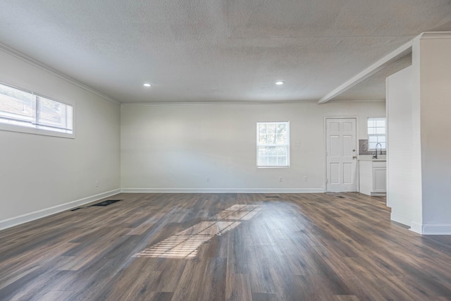 unfurnished room with beamed ceiling, ornamental molding, a textured ceiling, and dark wood-type flooring