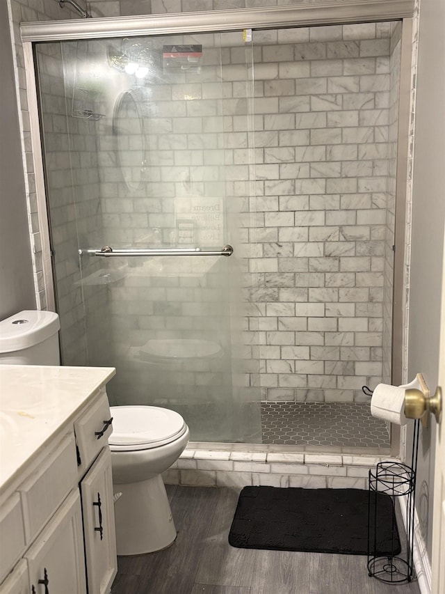 bathroom with hardwood / wood-style flooring, toilet, walk in shower, and vanity