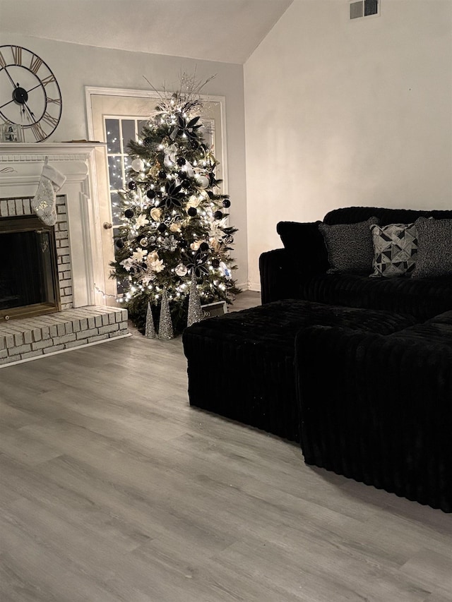 living room featuring vaulted ceiling, a fireplace, and hardwood / wood-style flooring