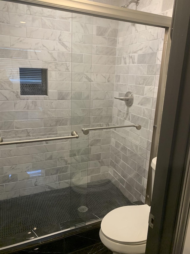 bathroom featuring toilet and a shower with door