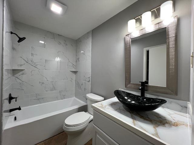 full bathroom with toilet, vanity, and tiled shower / bath