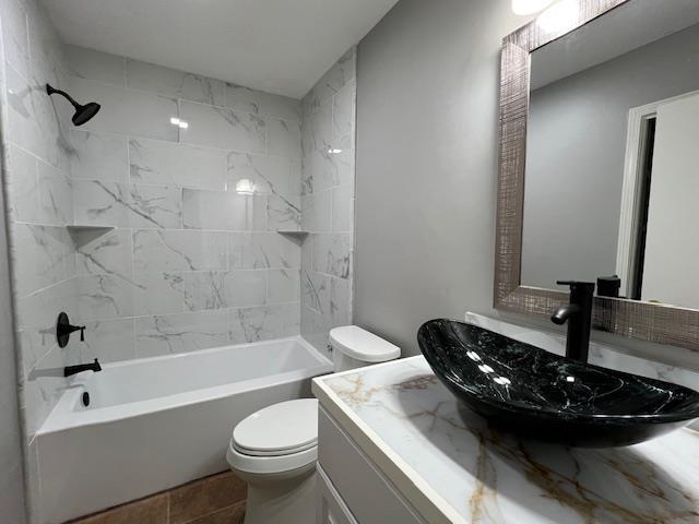 full bathroom with vanity, tiled shower / bath combo, and toilet