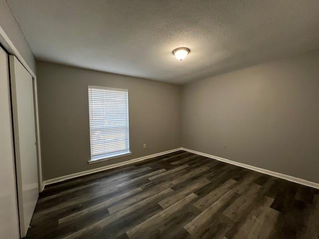 unfurnished bedroom with dark hardwood / wood-style floors, a textured ceiling, and a closet