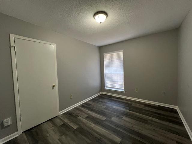 empty room with dark hardwood / wood-style flooring and a textured ceiling