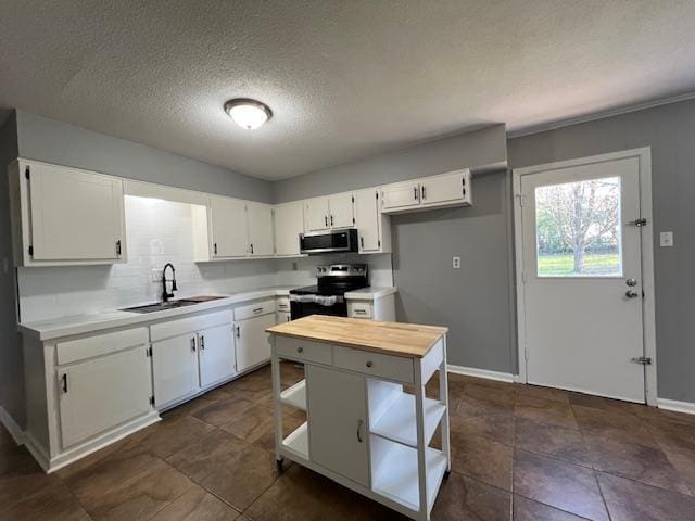 kitchen featuring sink, stainless steel appliances, dark tile patterned floors, a textured ceiling, and white cabinets