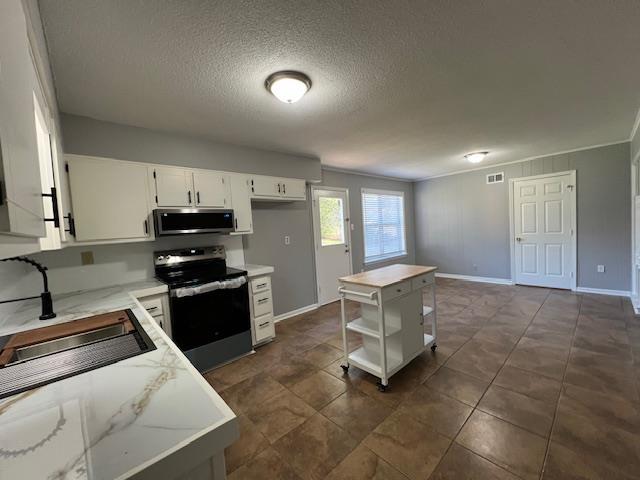 kitchen with white cabinetry, sink, a center island, a textured ceiling, and appliances with stainless steel finishes