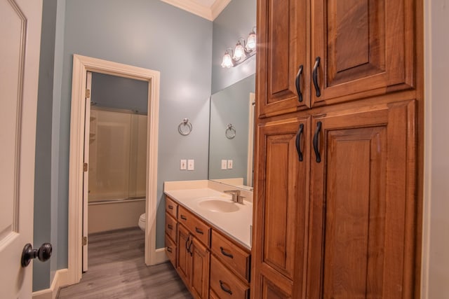 full bathroom featuring vanity, combined bath / shower with glass door, hardwood / wood-style flooring, toilet, and ornamental molding