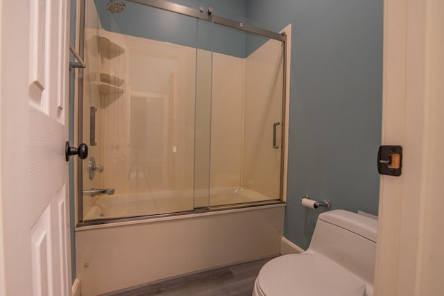 bathroom featuring hardwood / wood-style floors, toilet, and bath / shower combo with glass door