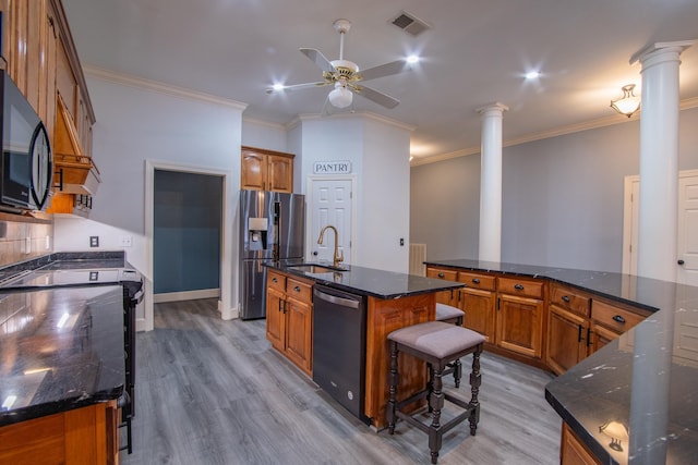 kitchen featuring a large island, ornate columns, sink, and appliances with stainless steel finishes