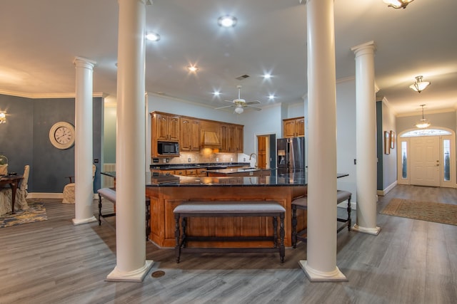 kitchen featuring decorative backsplash, stainless steel refrigerator with ice dispenser, black microwave, ceiling fan, and hardwood / wood-style floors