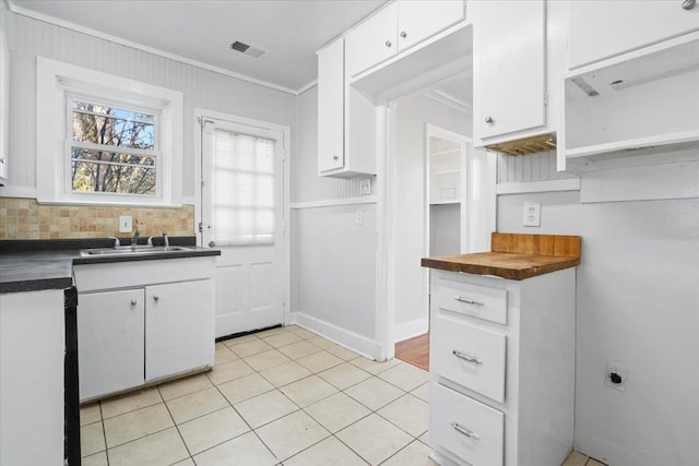 kitchen with white cabinetry, sink, light tile patterned floors, and crown molding