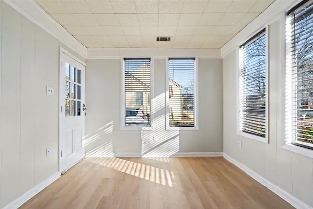 empty room with light wood-type flooring and crown molding