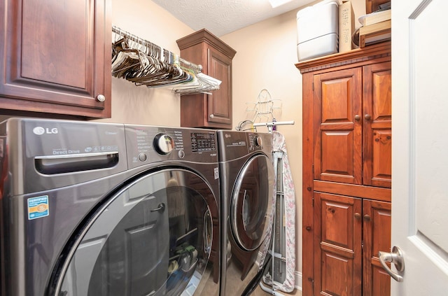 laundry room with washer and dryer, cabinets, and a textured ceiling