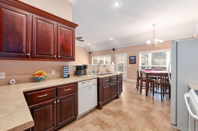 kitchen featuring sink, pendant lighting, vaulted ceiling, white appliances, and ceiling fan with notable chandelier